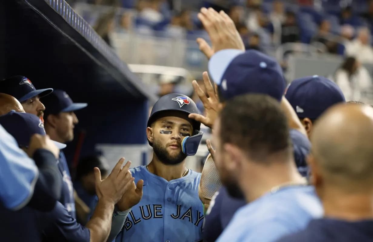 Toronto Blue Jays shortstop Bo Bichette (11) celebrates in the dugout with teammates after scoring against the Miami Marlins during the tenth inning at loanDepot Park.