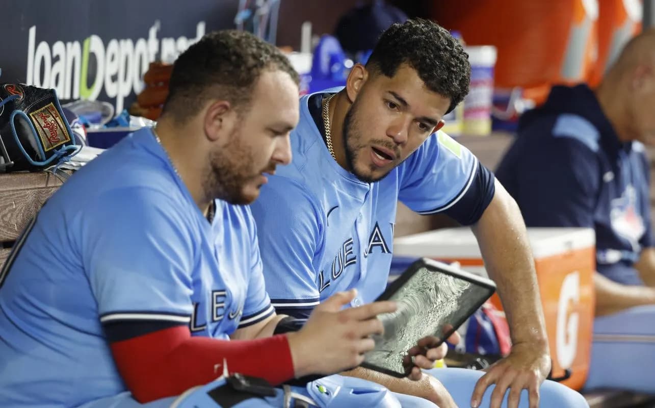 Toronto Blue Jays catcher Alejandro Kirk (30) and Toronto Blue Jays starting pitcher Jose Berrios (17) look at a tablet in the dugout against the Miami Marlins during the sixth inning at loanDepot Park.