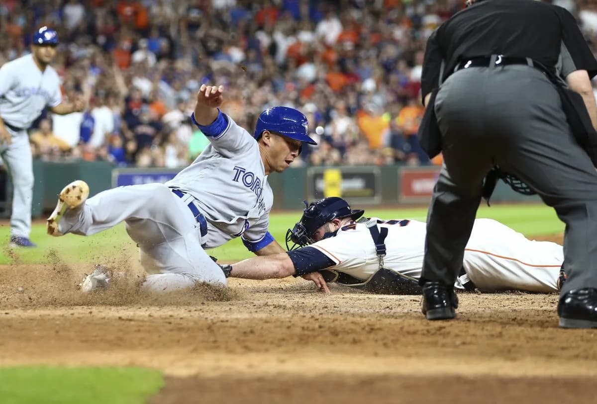 Toronto Blue Jays second baseman Rob Refsnyder (39) reaches home to score a run as Houston Astros catcher Brian McCann (16) applies the tag during the tenth inning at Minute Maid Park.