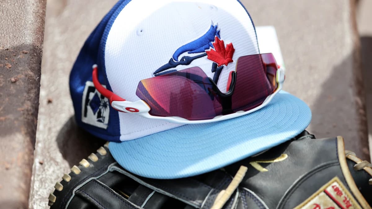 A detail view of a Toronto Blue Jays hat , sunglasses and glove laying in the dugout against the Atlanta Braves at CoolToday Park.