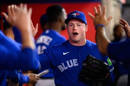 Toronto Blue Jays pitcher Louis Varland (77) is greeted by teammates after a pitching change during the eighth inning against the Los Angeles Angels at Angel Stadium.