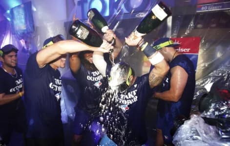 Toronto Blue Jays pitcher Jose Berrios (left) and first baseman Vladimir Guerrero Jr. (centre) pour champagne on third baseman Santiago Espinal (5) after clinching a wild card berth after a series against the Tampa Bay Rays at Roge