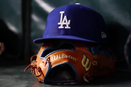 A detailed view of a Los Angeles Dodgers hat and glove on the bench against the Atlanta Braves in the eighth inning at Truist Park.