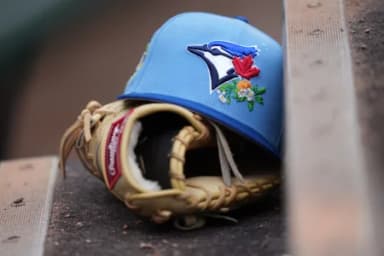 Detail photo. A Toronto Blue Jays hat and glove rest on the first base dugout steps at Roger Dean Chevrolet Stadium before the game against the Miami Marlins
