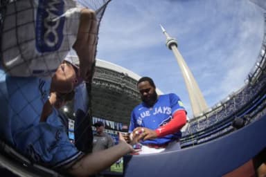 Toronto Blue Jays designated hitter Vladimir Guerrero Jr. (27) gives a fan an autograph before a game against the Cincinnati Reds at Rogers Centre.