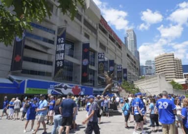 Fans gather around a statue of Joe Carter to commemorate the Toronto Blue Jays back to back World Series wins out side of Rogers Centre before a game between the Tampa Bay Rays and Toronto Blue Jays