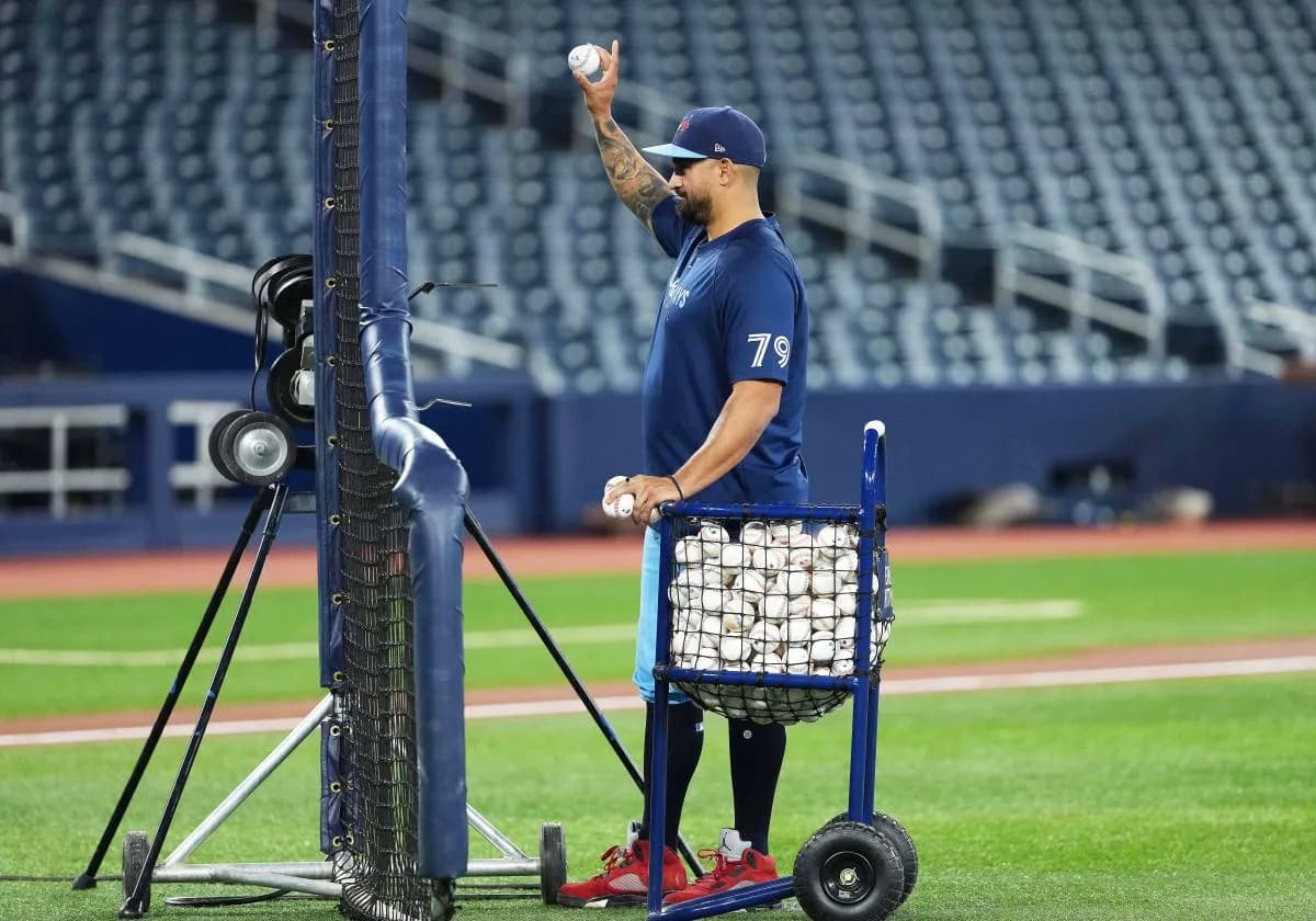 Toronto Blue Jays hitting coach David Popkins (79) uses the pitching machine to pitch balls during early batting practice before a game against the Baltimore Orioles at Rogers Centre.