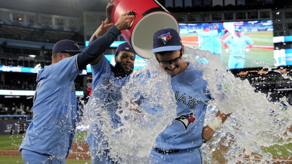 Toronto Blue Jays left fielder Davis Schneider (center) gets doused with ice water by center fielder Myles Straw (3) and first baseman Vladimir Guerrero Jr. (27) after a win over the Los Angeles Dodgers at Rogers Centre.