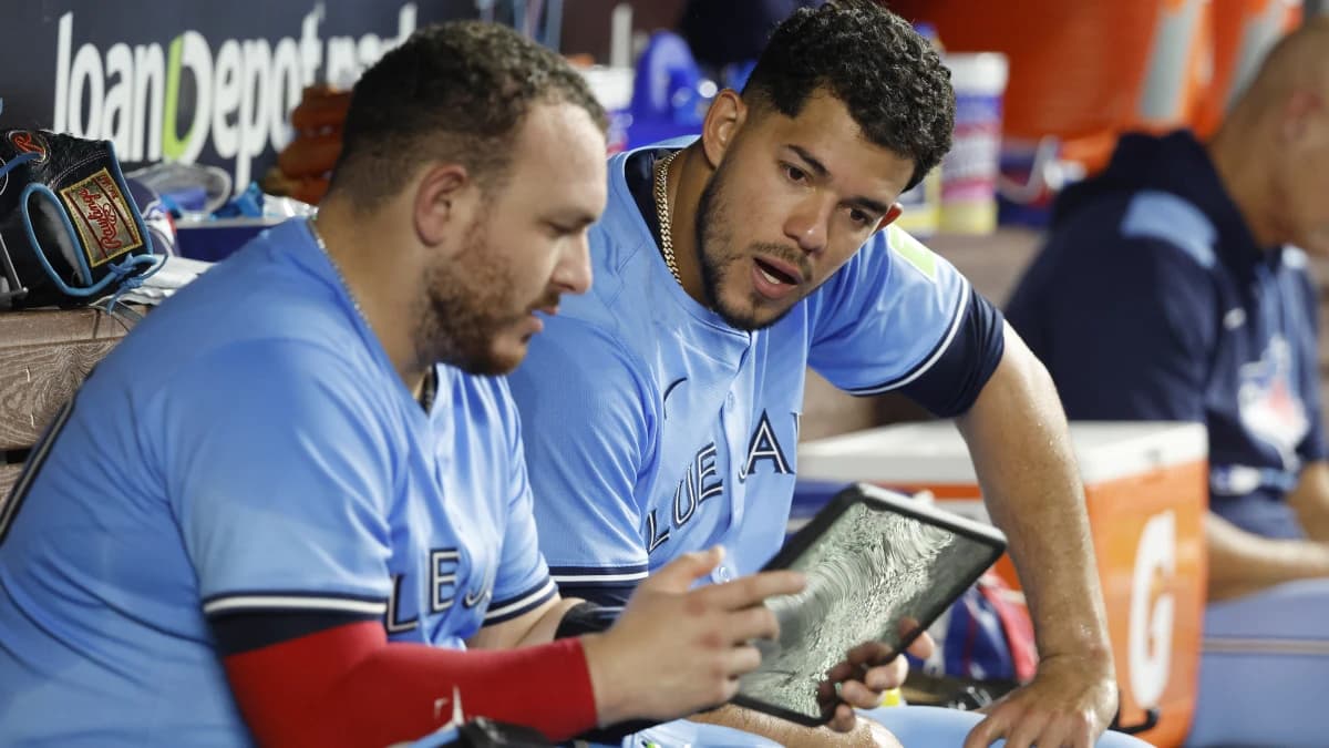 Toronto Blue Jays catcher Alejandro Kirk (30) and Toronto Blue Jays starting pitcher Jose Berrios (17) look at a tablet in the dugout against the Miami Marlins during the sixth inning at loanDepot Park.