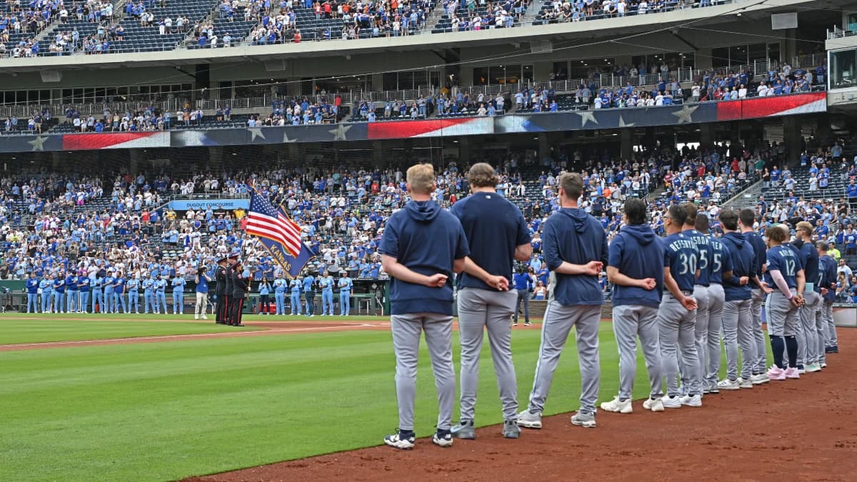 The Seattle Mariners and Kansas City Royals stand during the national anthem at Kauffman Stadium.