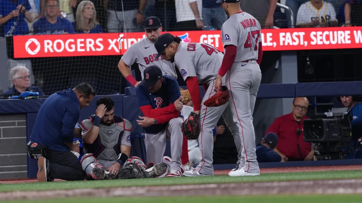 Boston Red Sox catcher Connor Wong (12) is attended to by the training staff during the seventh inning against the Toronto Blue Jays at Rogers Centre