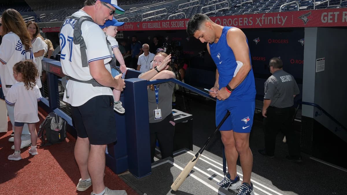 Toronto Blue Jays shortstop Andrés Giménez (0) signs autographs during batting practice before a game against the New York Yankees at Rogers Centre.