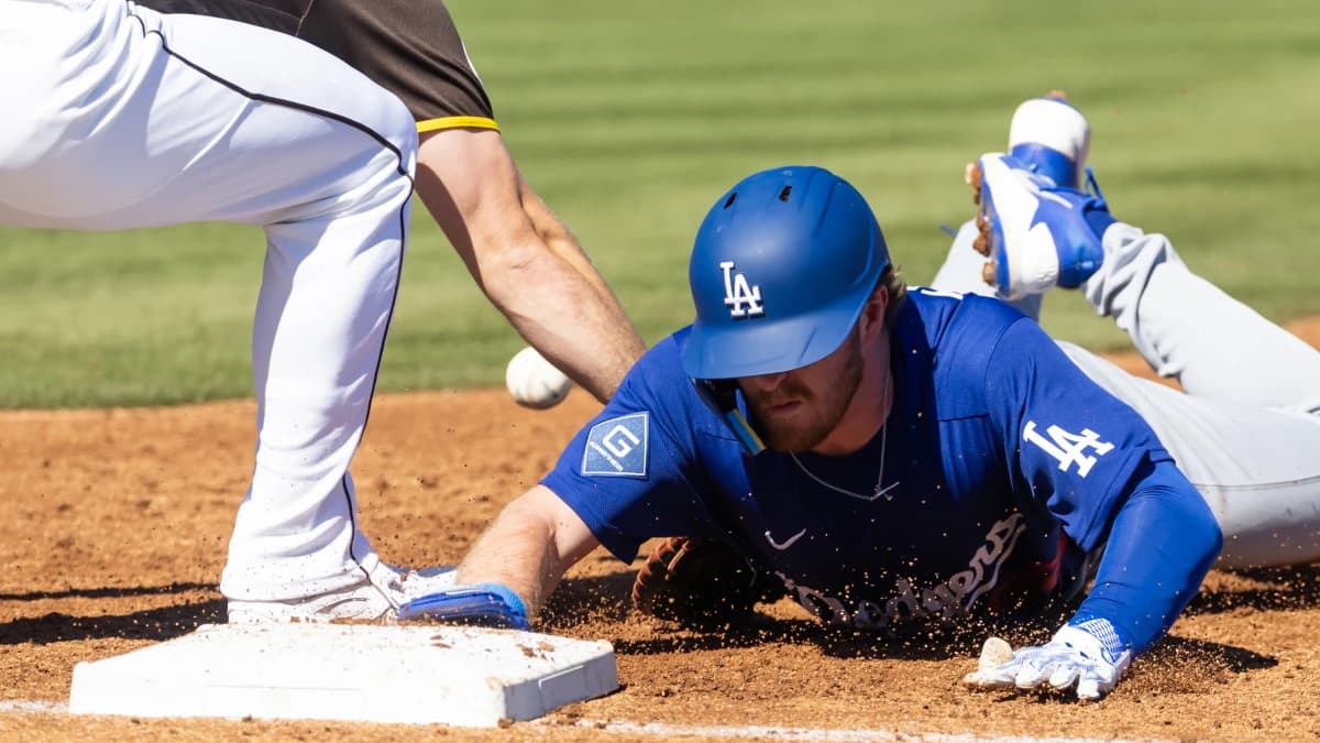 Los Angeles Dodgers base runner James Tibbs III dives back to first base on a pickoff attempt against the San Diego Padres during a spring training game at Peoria Sports Complex