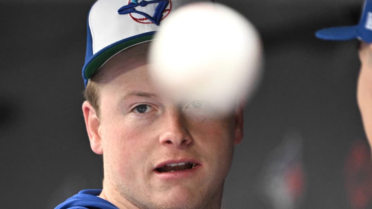 Toronto Blue Jays relief pitcher Louis Varland (77) tosses a baseball as he talks with team mates before playing the Seattle Mariners at Rogers Centre