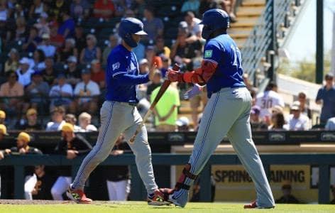Toronto Blue Jays shortstop Andres Gimenez (0) is congratulated by Toronto Blue Jays first baseman Vladimir Guerrero Jr. (27) after he scored a run during the fifth inning against the Pittsburgh Pirates at LECOM Park.