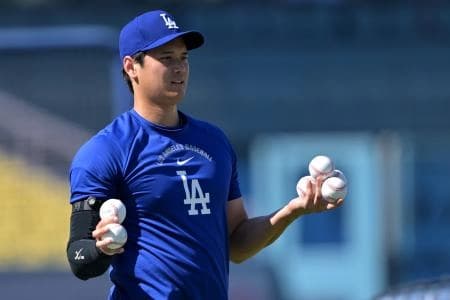 Los Angeles Dodgers two-way player Shohei Ohtani (17) helps pick up balls after taking live batting practice prior to the game against the Cleveland Guardians at Dodger Stadium.