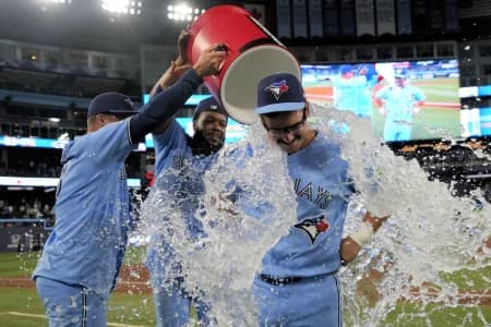 Toronto Blue Jays left fielder Davis Schneider (center) gets doused with ice water by center fielder Myles Straw (3) and first baseman Vladimir Guerrero Jr. (27) after a win over the Los Angeles Dodgers at Rogers Centre.