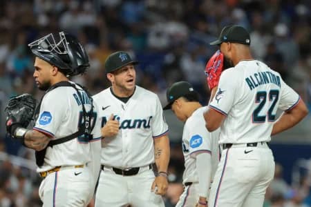 Miami Marlins pitching coach Daniel Moskos (57) speaks to starting pitcher Sandy Alcantara (22) during a mound visit against the Colorado Rockies in the fourth inning at loanDepot Park.