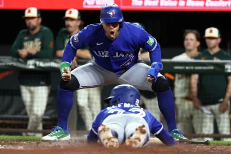 Toronto Blue Jays designated hitter George Springer (4) celebrates as Toronto Blue Jays shortstop Ernie Clement (22) slides home to score a run during the eighth inning against the Baltimore Orioles at Oriole Park at Camden Yards.