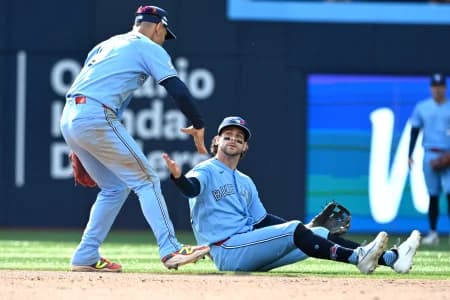 Toronto Blue Jays second baseman Ernie Clement (22) is greeted by shortstop Andres Gimenez (0) after throwing out Baltimore Orioles first baseman Pete Alonso (not shown) while sitting on the ground in the eighth inning at Rogers Centre.