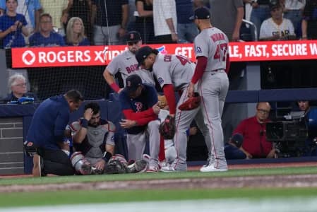 Boston Red Sox catcher Connor Wong (12) is attended to by the training staff during the seventh inning against the Toronto Blue Jays at Rogers Centre