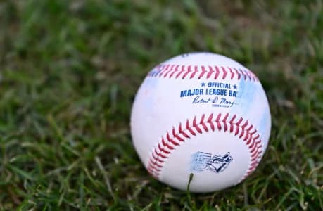 An official MLB baseball with a Toronto Blue Jays logo sits on the grass before a game against the Boston Red Sox at Fenway Park.