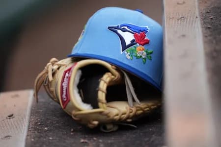 Detail photo. A Toronto Blue Jays hat and glove rest on the first base dugout steps at Roger Dean Chevrolet Stadium before the game against the Miami Marlins .