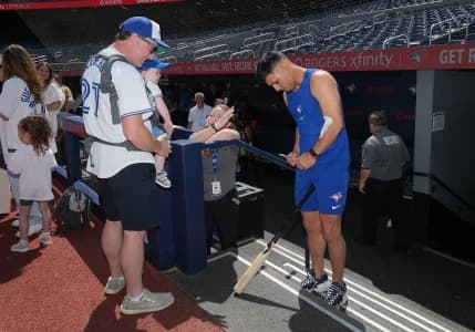 Toronto Blue Jays shortstop Andrés Giménez (0) signs autographs during batting practice before a game against the New York Yankees at Rogers Centre.
