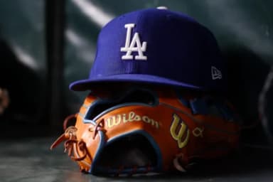 A detailed view of a Los Angeles Dodgers hat and glove on the bench against the Atlanta Braves in the eighth inning at Truist Park.