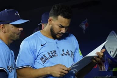 Toronto Blue Jays designated hitter Anthony Santander (25) and second baseman Andres Gimenez (0) review a playbook before a game against the Cleveland Guardians at Rogers Centre.