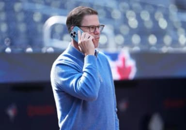 Toronto Blue Jays general manager Ross Atkins talks on the phone during batting practice before a game against the Baltimore Orioles at Rogers Centre